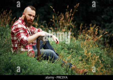 Lumberjack assis en se reposant après un travail acharné de la forêt Banque D'Images