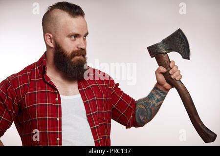 Homme barbu tenant une hache et posing in studio Banque D'Images