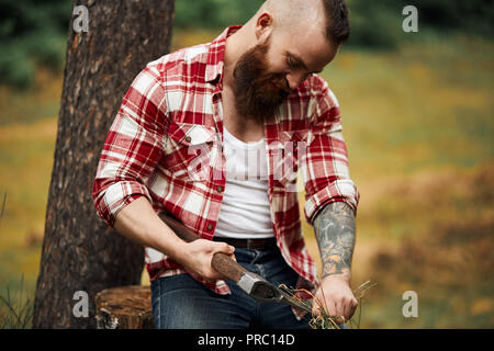 Homme barbu propres lingettes ax avec des feuilles. Axeman barbu. Banque D'Images