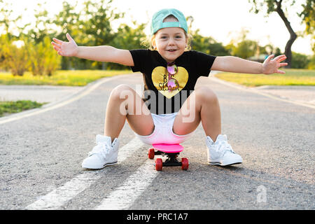 Child riding skateboard park en été. Petite fille à apprendre à faire du vélo skate board. Sport actif à l'extérieur pour l'école et le jardin d'enfants. Enfants planche à roulettes. Bambin sur longboard. Patinage artistique pour enfants Banque D'Images