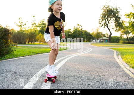 Child riding skateboard park en été. Petite fille à apprendre à faire du vélo skate board. Sport actif à l'extérieur pour l'école et le jardin d'enfants. Enfants planche à roulettes. Bambin sur longboard. Patinage artistique pour enfants Banque D'Images