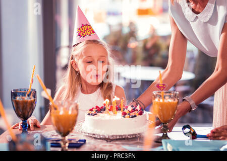 Fille d'anniversaire avec ses bougies et en soufflant sur le gâteau Banque D'Images