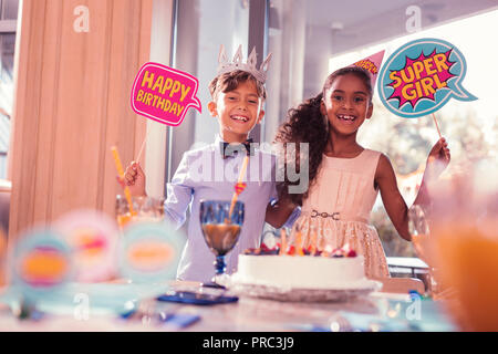 Cheerful girl holding fille super signer alors qu'il se tenait avec ami Banque D'Images
