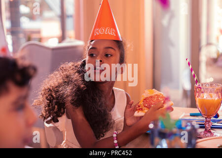 Fille à la faim dans la distance à la mastication pizza Banque D'Images