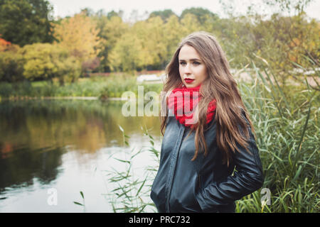 Jeune femme à l'automne en plein air portrait. Fille en veste noire et foulard rouge Banque D'Images