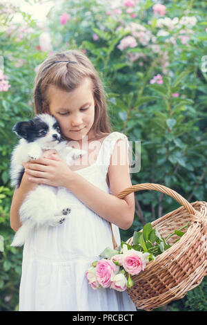 Petite fille tenant un chiot dans ses bras dans le jardin Banque D'Images