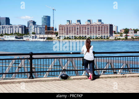 Jeune femme rousse regardant le paysage de la ville de Montréal et le fleuve Saint-Laurent sur une journée ensoleillée au Québec, Canada. Banque D'Images