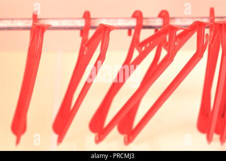 Cintres en plastique rouge dans une armoire vide. Bokeh doux et Banque D'Images