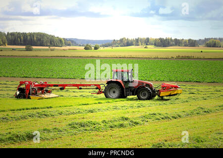 Salo, Finlande - le 23 septembre 2018 : coupe du foin sur les terres agricoles à NOVACAT T Faucheuse à disque traîné tiré par le tracteur CASE IH CS120 sur une belle journée. Banque D'Images