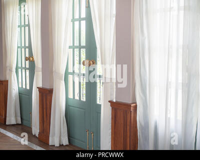 La lumière à travers la voir à travers des rideaux blancs de l'extérieur avec portes en bois vert vintage house dans un style contemporain. Banque D'Images