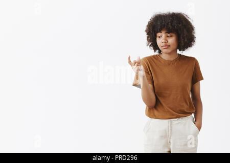 Vous kall il taille. Indifférent et insouciant indifférent cute african american female student with afro hairstyle façonner petit ou petit objet avec les doigts à la mains à contrarié et mécontent Banque D'Images