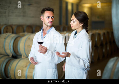 Deux jeunes winery employés en blouse blanche de qualité du vin et vieillissement L'article sur winery manufactory Banque D'Images