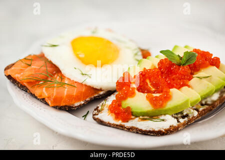 L'avocat et caviar rouge, saumon fumé et œuf frit toasts de seigle pour le petit-déjeuner, Close up Banque D'Images