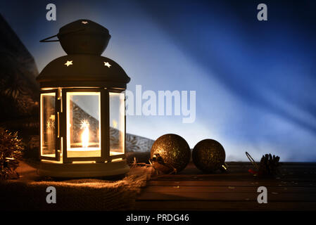 Composition avec lanterne allumée et décoration de Noël sur la table en bois dans l'obscurité. Composition horizontale Banque D'Images
