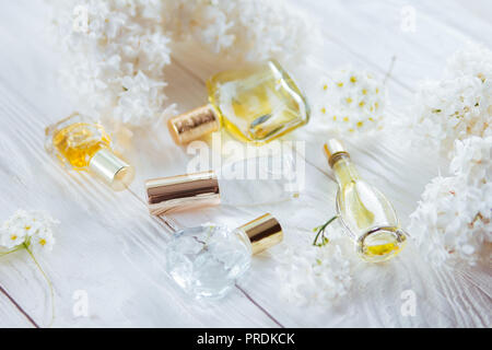 Flacons de parfum avec des fleurs blanches sur fond de bois Banque D'Images