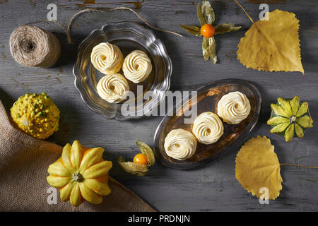 Mise à plat avec des guimauves (zephyr, meringue) fait avec décoration de citrouilles, les citrouilles et les feuilles d'automne jaune foncé sur fond rustique Banque D'Images