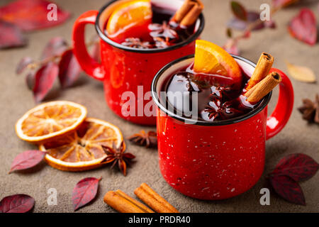 Deux tasses de vin chaud de l'automne ou gluhwein avec des épices et des tranches d'orange sur la table rustique vue d'en haut. Boisson traditionnelle de l'automne maison de vacances dans l'arrière-plan des feuilles d'automne Banque D'Images