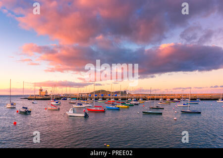Incroyable coucher du soleil à Howth, Dublin, Irlande. La vue sur le phare de Howth et bateaux colorés à l'avant-plan. Banque D'Images