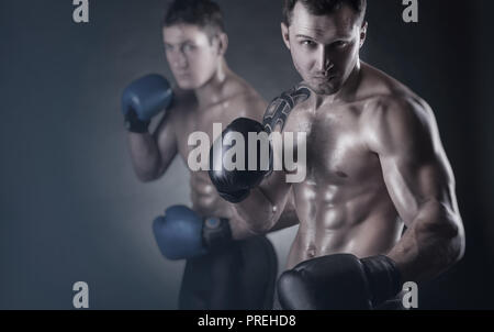 Deux boxer avec des gants de boxe avant un combat contre un fond sombre Banque D'Images