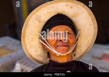 Fermier chinois woman wearing straw hat au marché de Niujiaozhai rural town, Yuanyang dans la province du Yunnan, Chine du sud. Banque D'Images