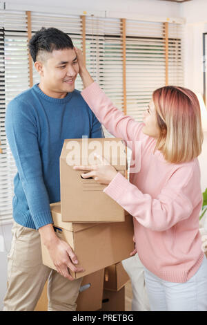 Happy asian couple transporter des boîtes de carton tout en se déplaçant pour nouvelle maison dans la salle de séjour.déballage pour nouvelle maison.femme essuyer la sueur son mari Banque D'Images