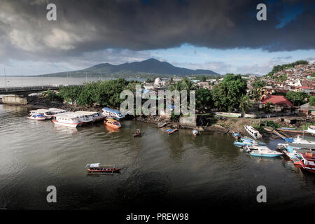 Taxi-bateau en bois ferry transporte des passagers de l'autre côté de la rivière à Manado, Sulawesi, Indonésie. L'île de Bunaken est à l'arrière-plan. Banque D'Images