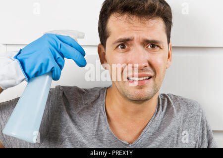 Les jeunes époux en crise de ménage. Close up of a souligné l'homme avec le matériel de nettoyage Banque D'Images