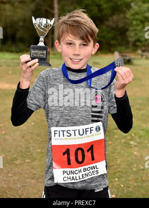 10 ans arborant fièrement sa médaille et la coupe après avoir remporté une course de 2,5 km course cross-country, Hindhead, Surrey, UK. 30 septembre 2018 Malik.