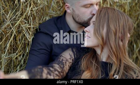 Histoire d'amour d'un jeune couple dans la nature. Le mec embrasse la jeune fille qui ferma les yeux et jouit de l'instant Banque D'Images