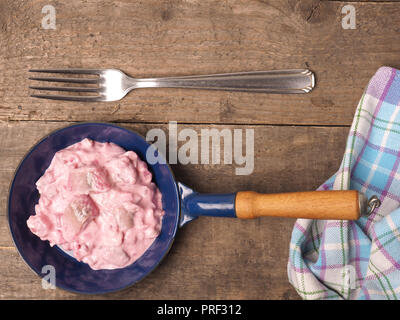 Hareng savoureux avec racine de betterave sauce dans une poêle de fer sur une table en bois Banque D'Images