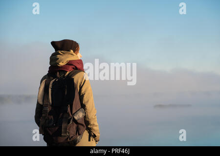 Femme se tient dans la lumière du soleil du matin en face de la belle nature paysage couvert de brouillard. Female hiker profitant soleil levant dans misty natural background Banque D'Images