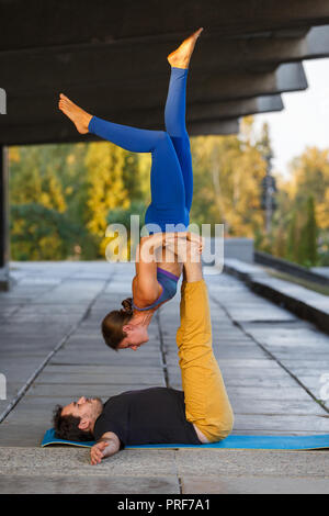 Jeune homme et girl practicing yoga acro en ville sur la rue Banque D'Images