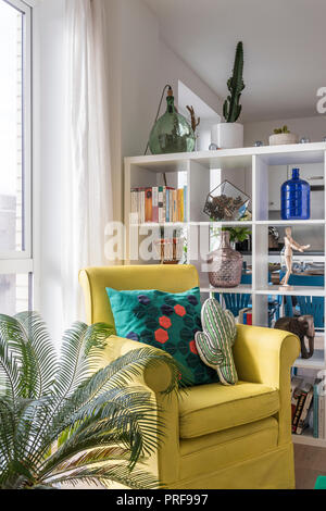 Nouveauté coussins sur fauteuil jaune avec étagère en appartement à Londres Banque D'Images