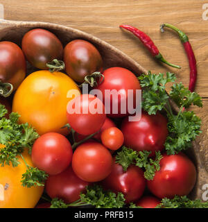 Place près des tomates biologiques colorés frais vert, le persil et les poivrons rouges. Mise à plat sur la surface de la table en bois naturel. Focus sélectif. En bonne santé Banque D'Images