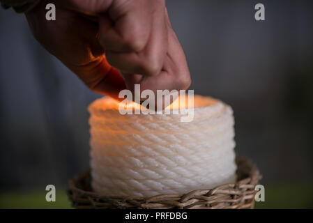 Bougie dans l'osier panier en bois debout sur la table à manger dans le restaurant ou sur le vert, lin naturel d'être allumé. Atmosphère romantique pour Banque D'Images