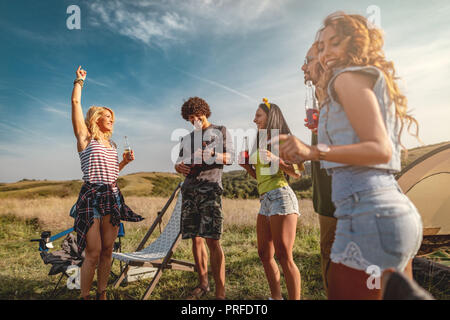 Les jeunes ont un bon temps au camp dans la nature. Ils se reposer, rire et chanter avec la musique d'ukulélé, heureux d'être ensemble. Banque D'Images