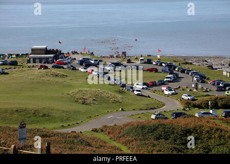 Un parking à Ogmore par mer plage sur une journée ensoleillée avec une grande foule de personnes dans la formation takingn excersises pour le sauvetage des personnes en mer. Banque D'Images