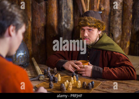 Deux hommes en costume ethnique russe populaire médiéval jeu jeu de stratégie - tafl. Folk, de concurrence et de concept traditionnel Banque D'Images