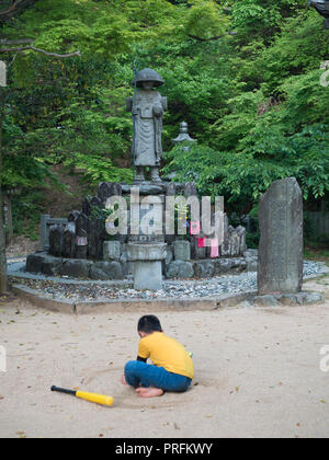 Enfant jouant, statue de Kobo Daishi, statues Jizo Bosatsu, un cercle dans le sable, Senyuji 58 temple, temple 88 Shikoku pèlerinage, Ehime, au Japon Banque D'Images