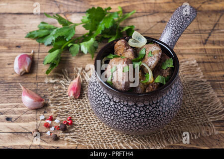 Foie de poulet au four avec l'oignon dans une cocotte en céramique sur une table rustique en bois Banque D'Images