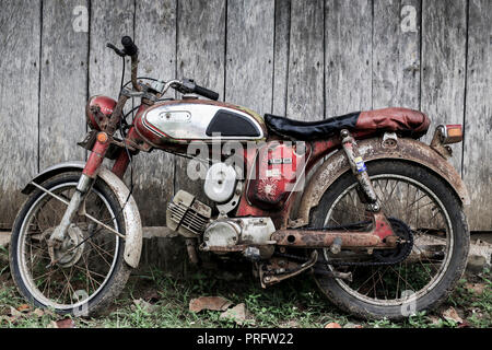 Vieille moto rouillée reposant sur un hangar en bois Banque D'Images
