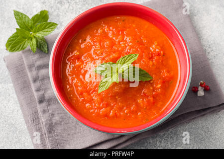 Soupe de tomate dans un bol en céramique sur une serviette avec des tranches de pain grillé Banque D'Images