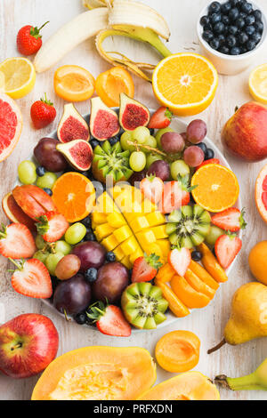 Assiette de fruits et baies, fraises, bleuets mango orange, pomme, raisins, kiwis sur le bois blanc, l'arrière-plan, Vue de dessus de l'espace de copie Banque D'Images