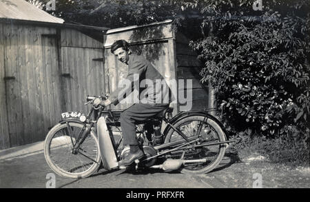 Jeune homme sur une 1923 Nouveau moto 250cc impériale en face de cabanes dans les années 1920 Banque D'Images