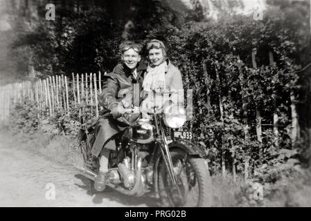 Sur l'homme 1938 Ariel Red Hunter moto avec femme debout à côté de lui country lane vers 1938 Banque D'Images