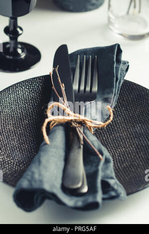 Table de fête dans un style noir chez les noirs des bougies sur un tableau blanc. Plaque avec fourchette et couteau sur une serviette en lin. Thanksgiving Halloween ou di Banque D'Images
