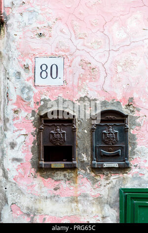 Les boîtes de courrier électronique et un numéro de maison '80' nom sur un mur rose en ruine sur l'île de Procida à Naples, Italie Banque D'Images