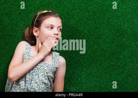 Petite fille est couchée sur le gazon artificiel et l'appel à quelqu'un. Banque D'Images