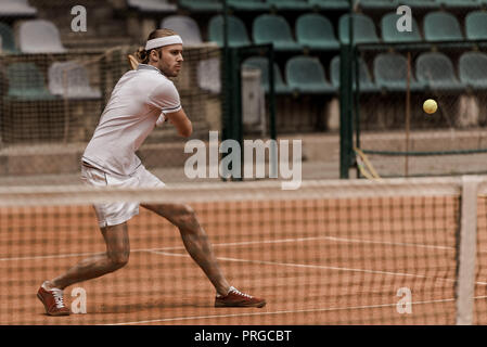 L'accent beau style rétro homme jouer au tennis à cour Banque D'Images