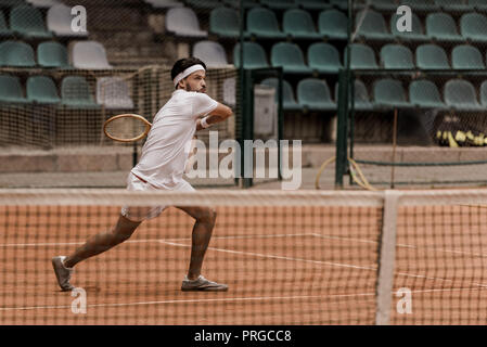 Beau concentré de style rétro homme jouer au tennis à cour Banque D'Images